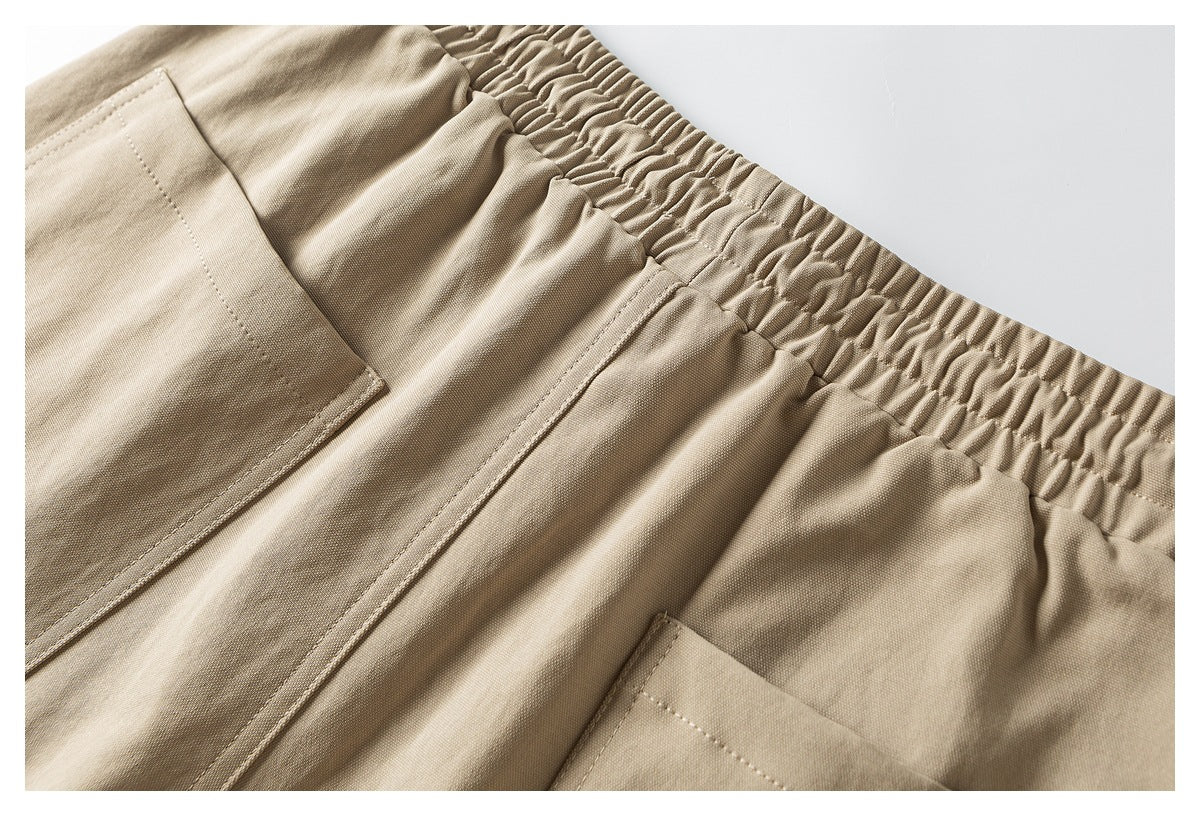 Close-up of tan trousers showing an elastic waistband and pocket openings.