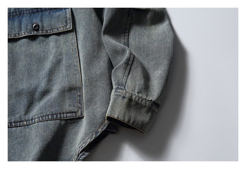 Close-up of the gray washed denim shirt’s long sleeve, cuff and edge of a front pocket.