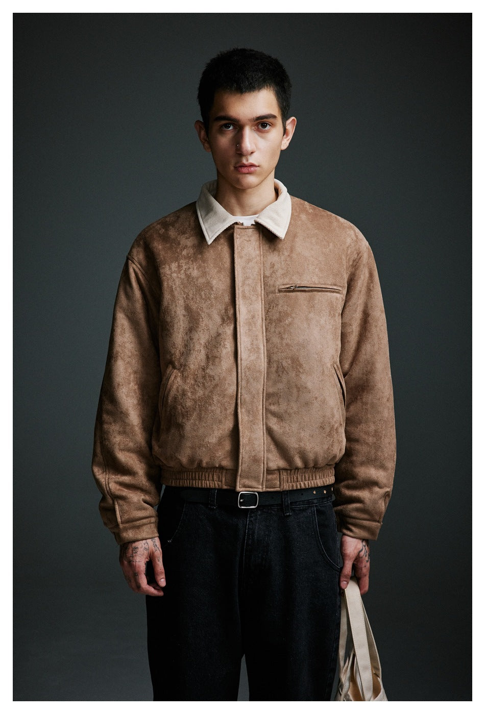 Front view of a model wearing a tan jacket with a cream collar, zip chest pocket, and elastic hem.