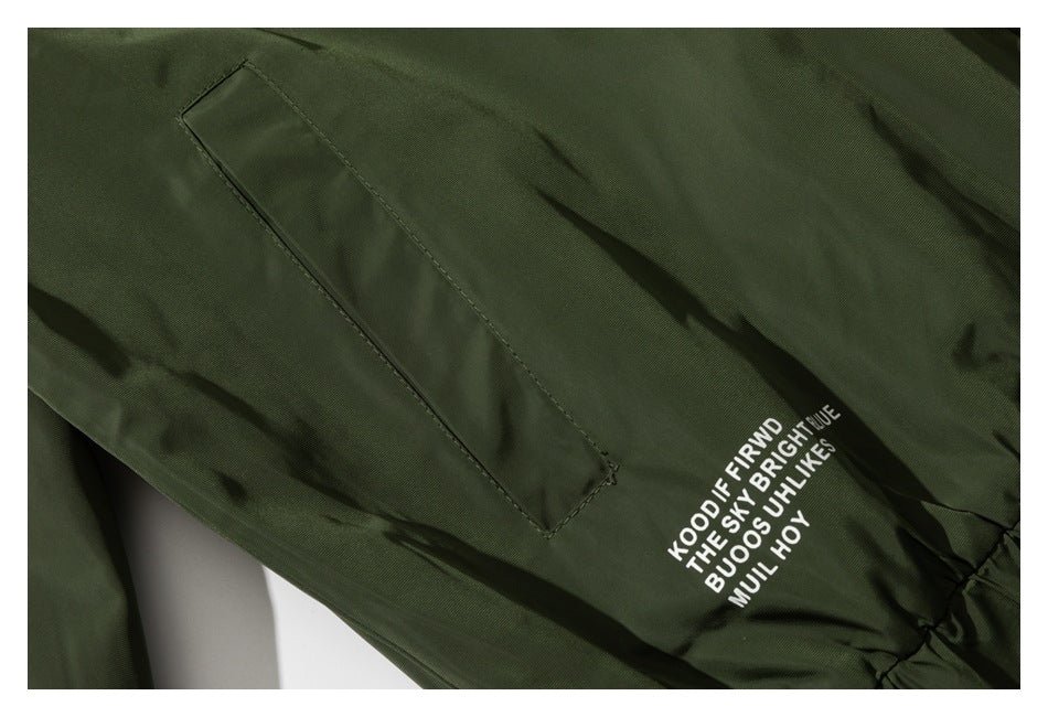 Dark olive jacket close-up showing a narrow pocket and white printed text near the gathered hem.