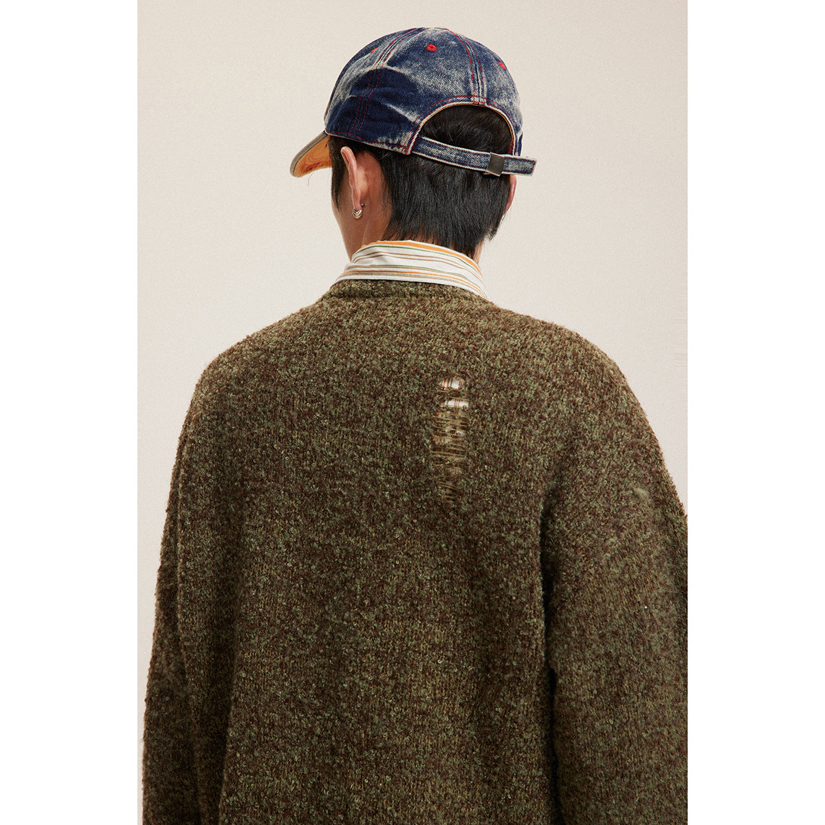 Back view of an olive-brown marled sweater with a distressed detail near the upper back.