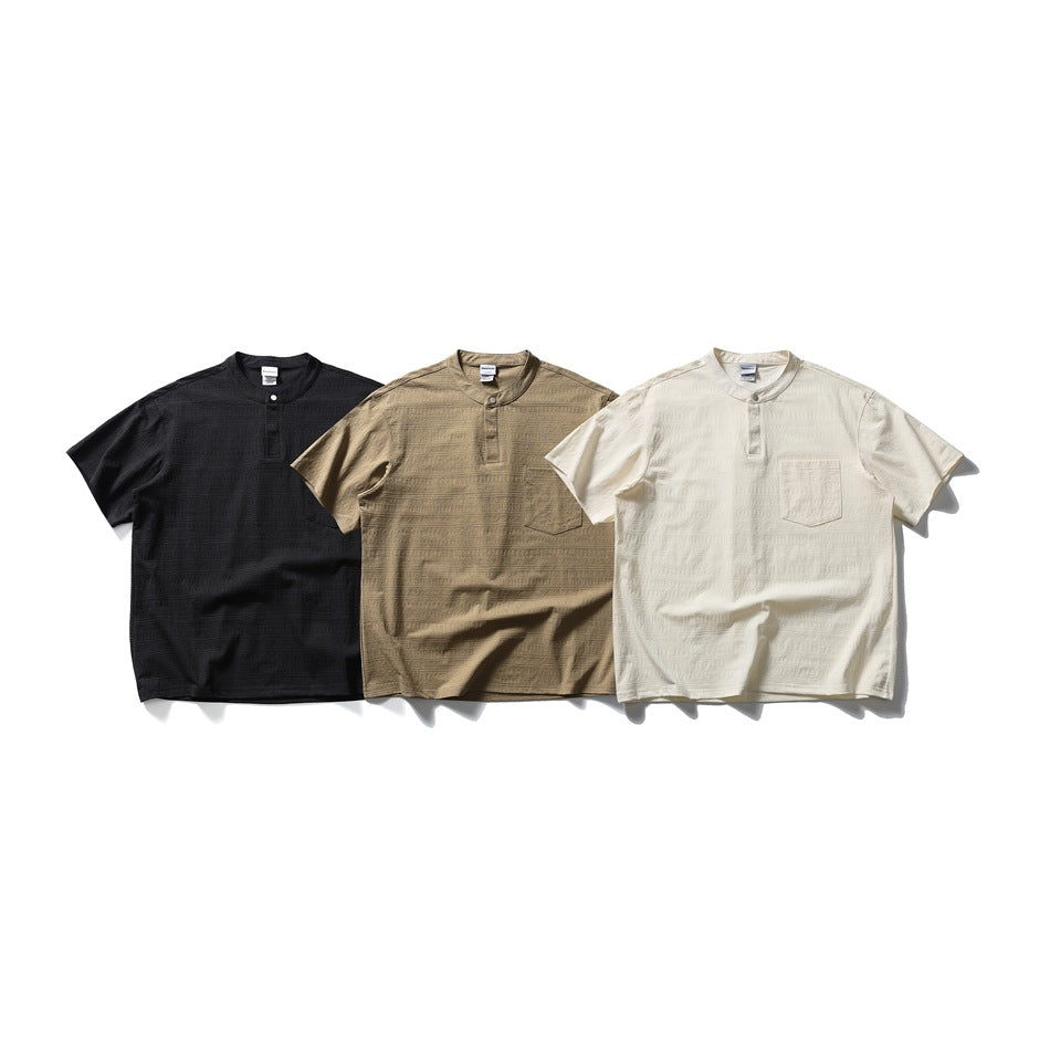 Three short-sleeve band-collar shirts with chest pockets in black, tan and off-white.