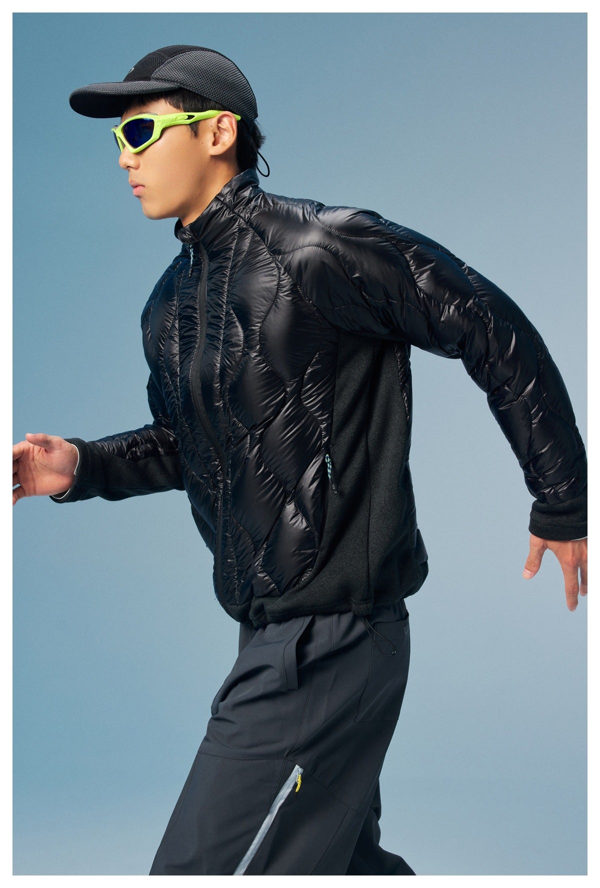 Side view of a man wearing a black quilted jacket with dark knit side panels and sleeves.