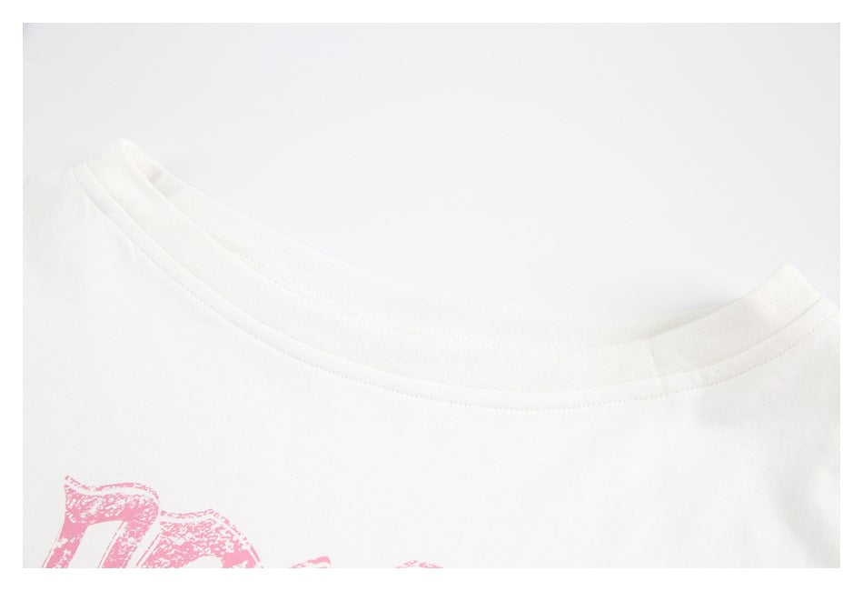 Close-up of the white T-shirt's crew neckline with part of a pink chest print visible.