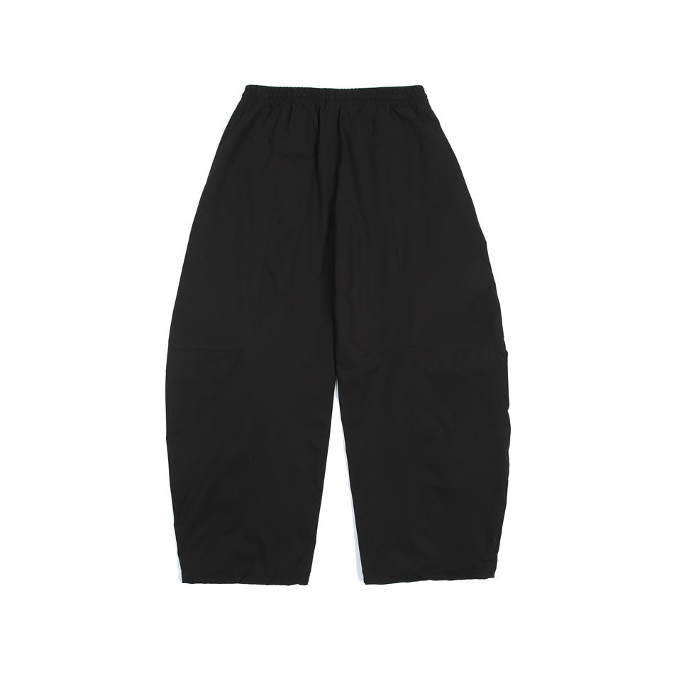 Back view of black loose-fit pants with an elastic waistband and large patch pockets.