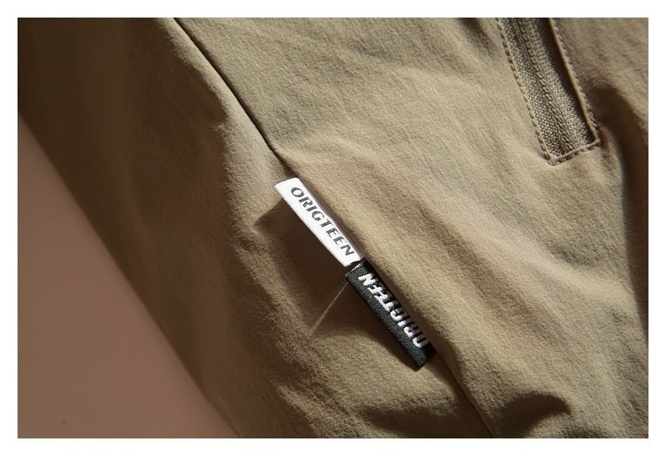 Close-up of an olive garment seam with two small woven brand tags.