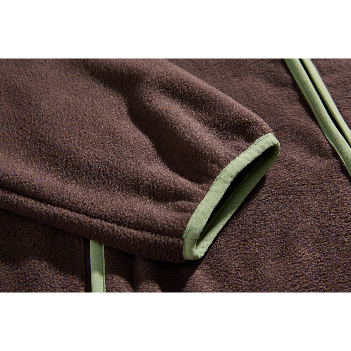 Close-up of a dark brown fleece sleeve cuff finished with pale green binding.