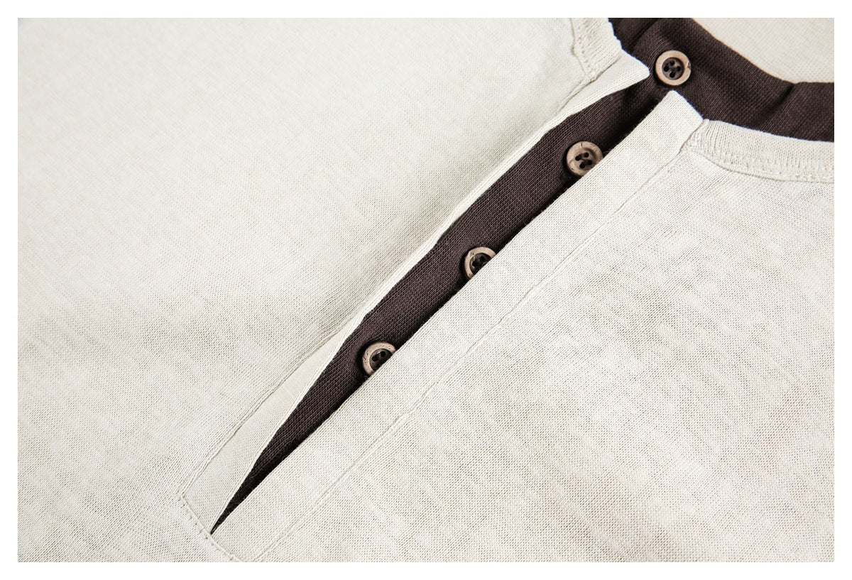 Close-up of a cream Henley placket over dark brown fabric, with brown buttons.