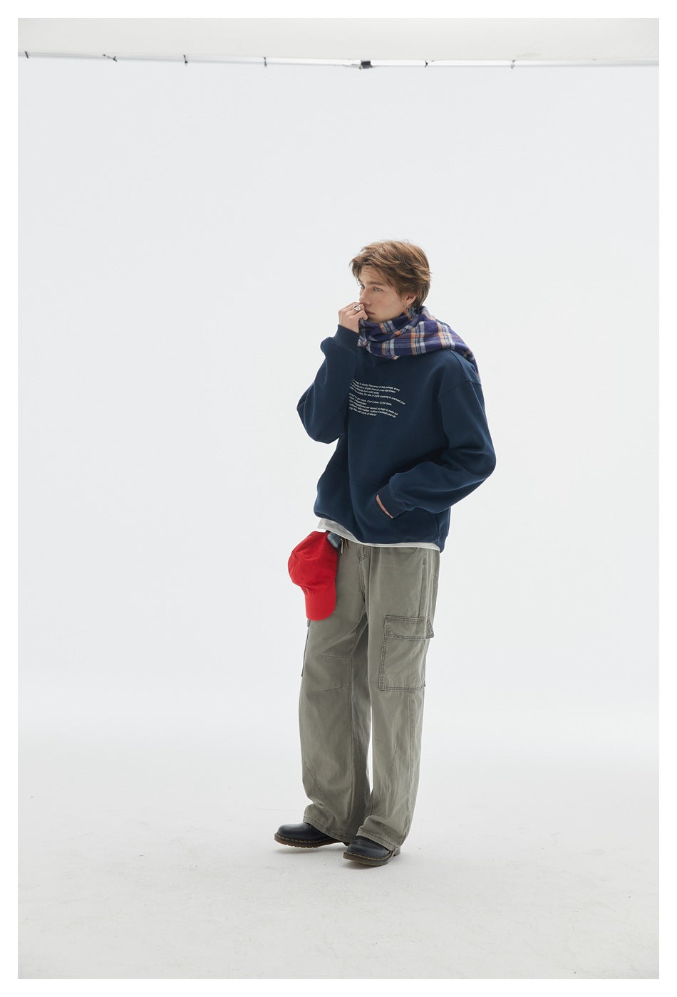 Model in a navy crewneck sweatshirt with small white text and olive cargo pants, shown at a three-quarter angle.