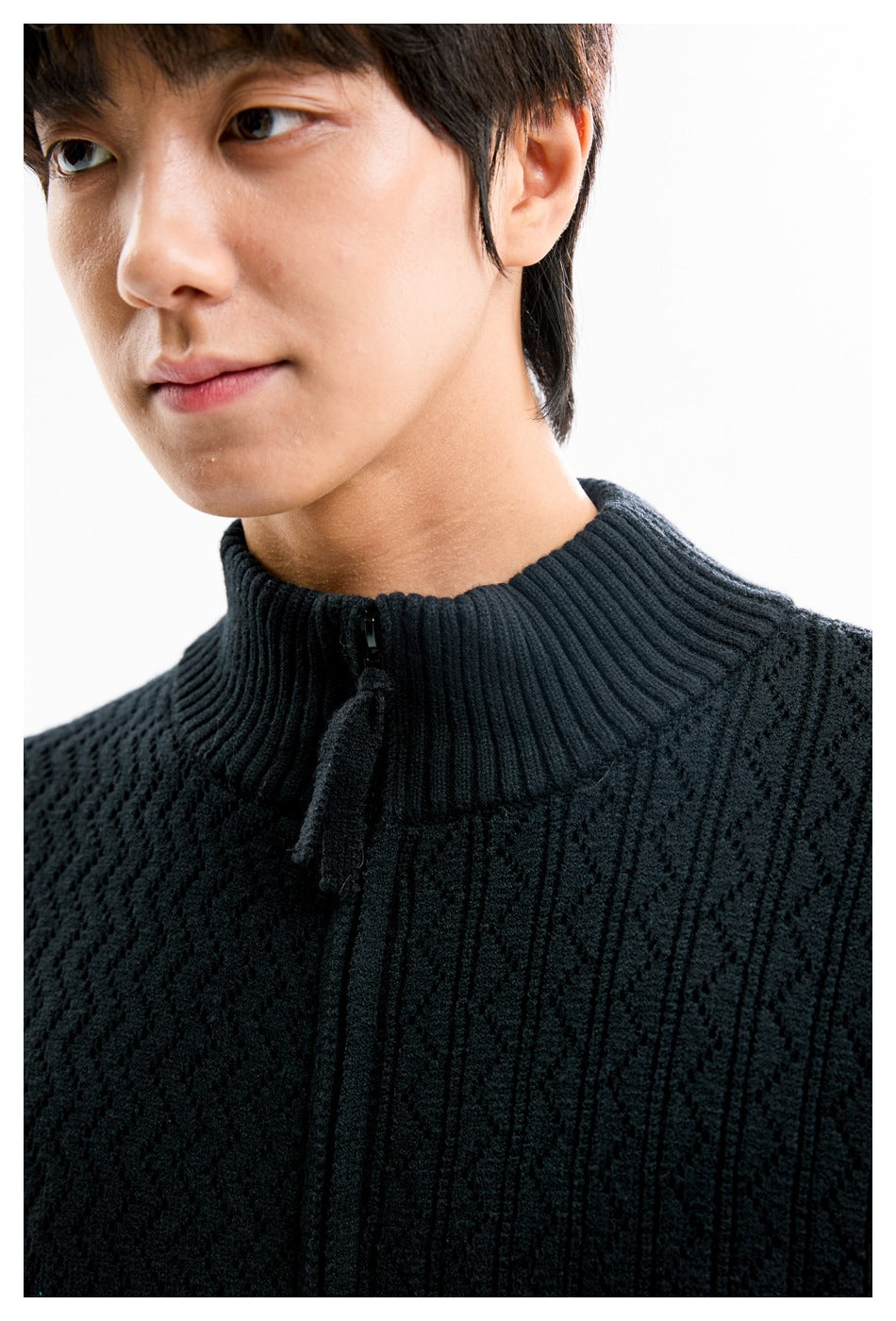 Close-up of a model wearing a black textured knit sweater with a ribbed stand collar and short front zipper.