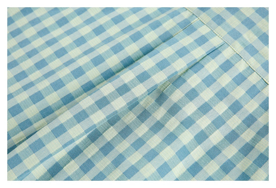 Close-up of blue and pale yellow checked shirt fabric with a stitched seam and folded edge.