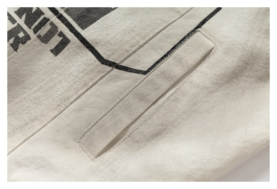 Close-up of a narrow welt pocket on the off-white jacket, with part of its black printed graphic at the edge.