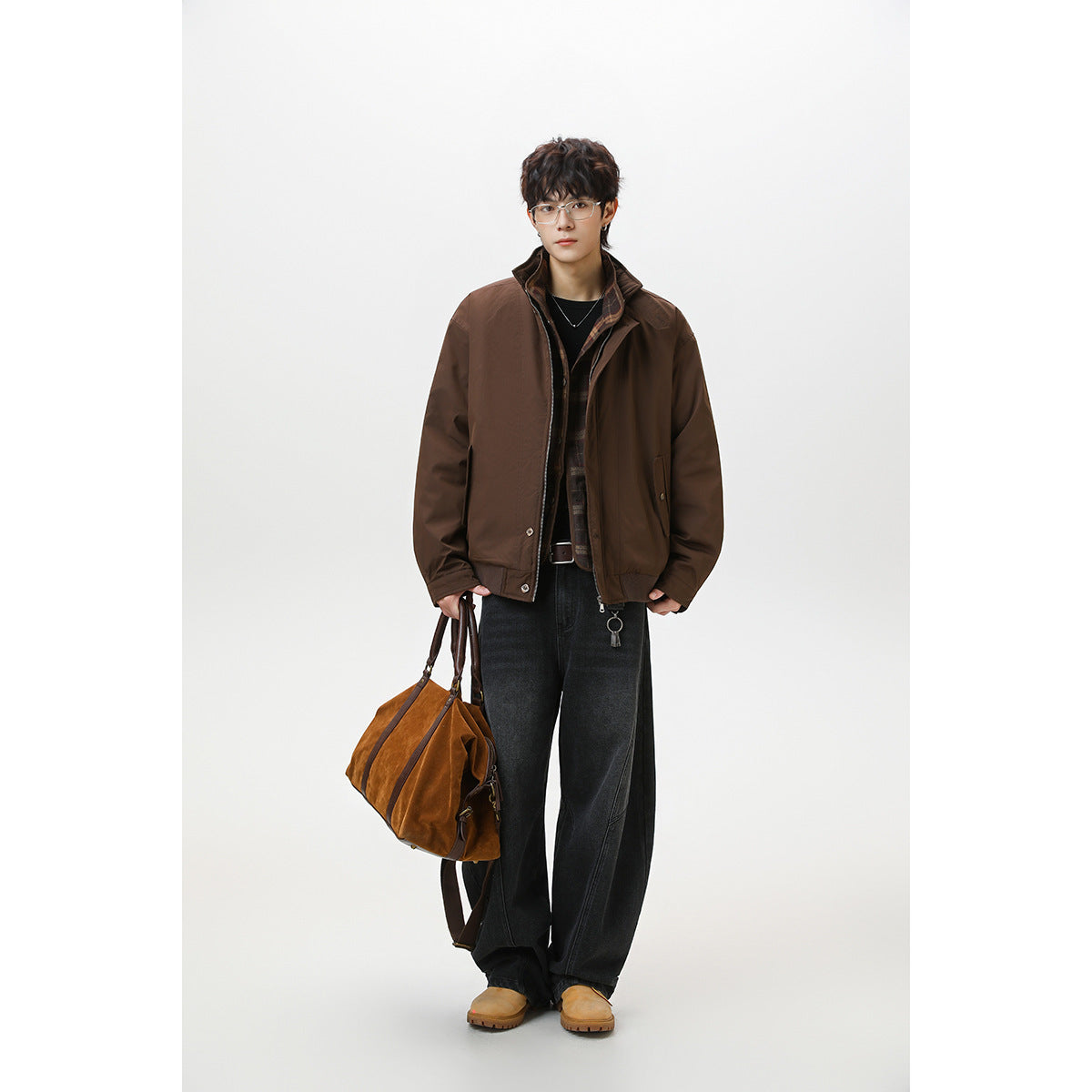 Full-length model wearing a brown zip-front jacket with a raised collar, black jeans, and tan shoes.
