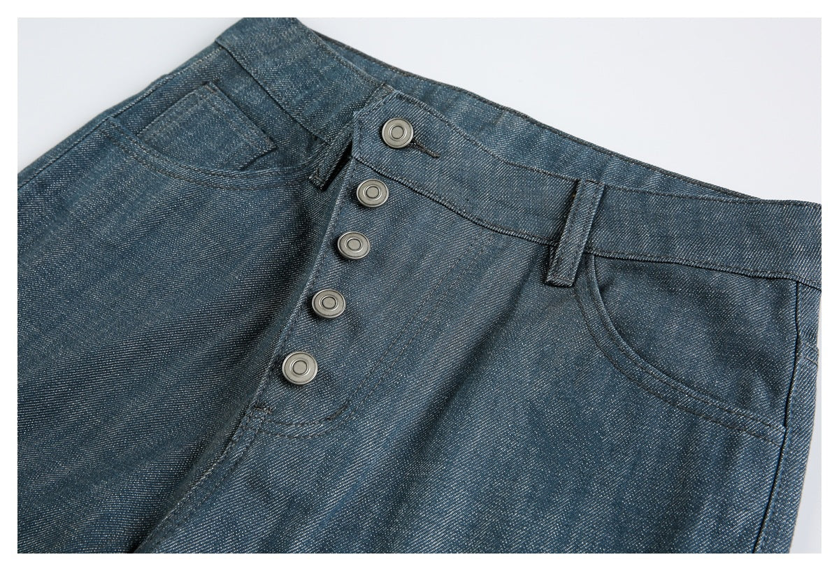 Close-up of dark blue pants showing the five-button front waistband, belt loops, and curved front pocket.