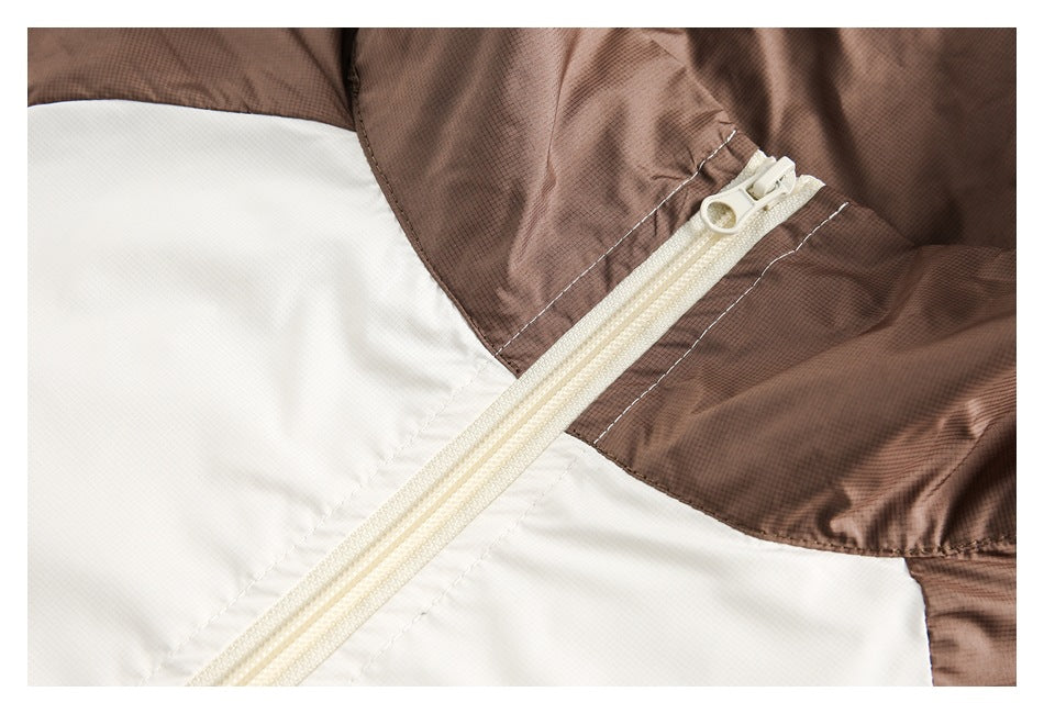 Close-up of the cream front zipper, stitching, and brown-and-white panels on a jacket.