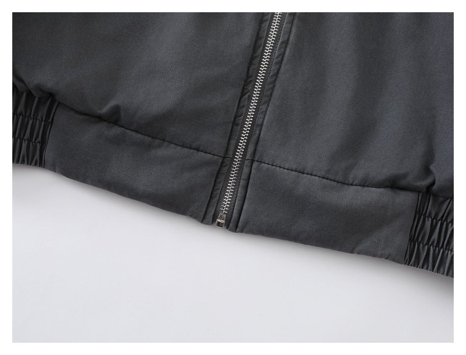 Close-up of the jacket's zippered front, elasticated waistband, and hem stitching.