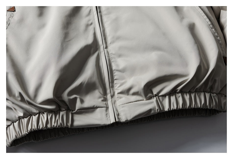 Close-up of the light gray jacket's front zipper seam and gathered elastic waistband.