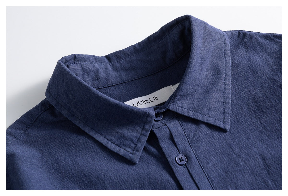 Close-up of a blue button-up shirt collar, front buttons, and sewn-in neck label.