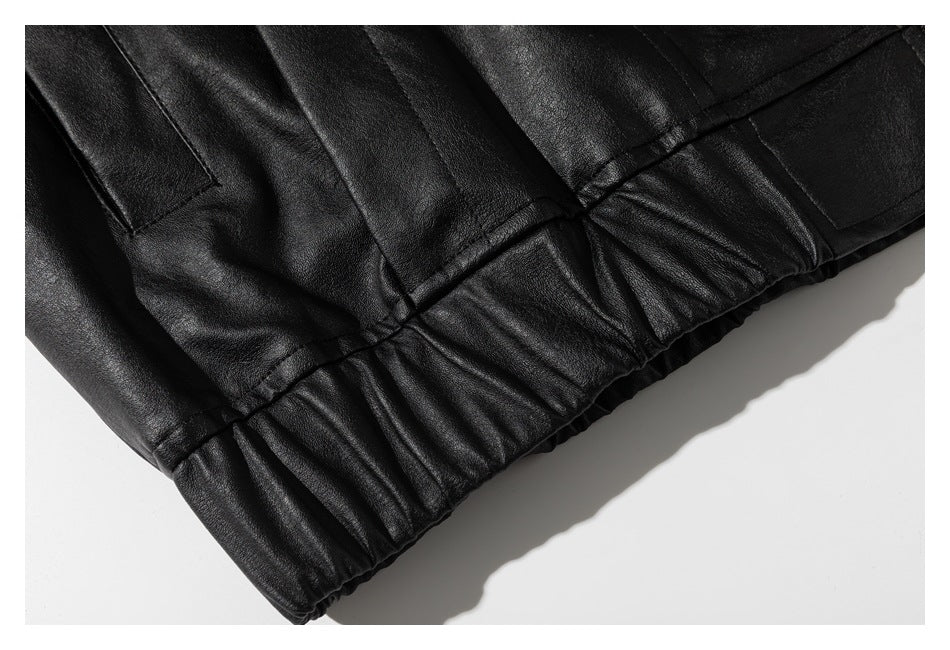 Close-up of a black leather-look garment's gathered elastic hem and stitched panels.