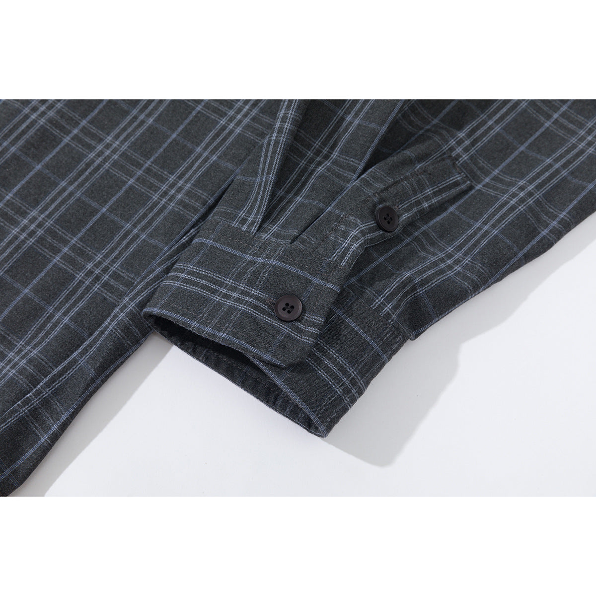 Close-up of the charcoal plaid shirt's buttoned cuff and sleeve.