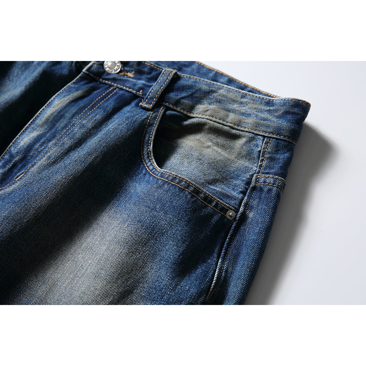 Close-up of a front pocket, belt loop, and faded blue denim on jeans.