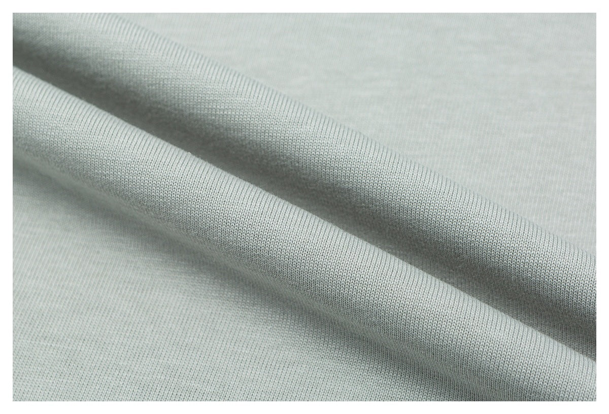 Close-up showing the smooth knit texture and soft folds of pale sage-gray fabric.