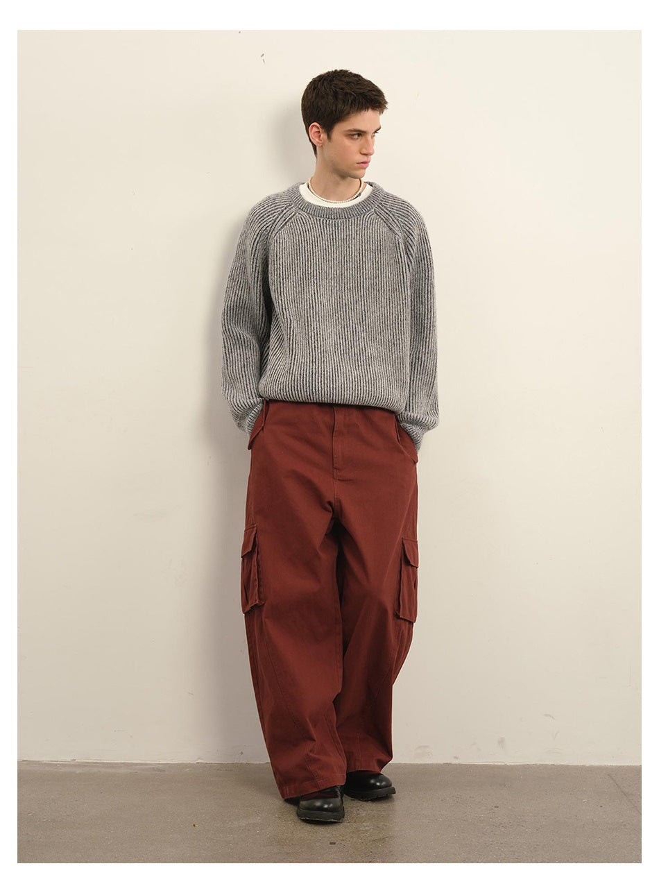 Full-length male model in a gray ribbed sweater, rust-red cargo pants, and black shoes.