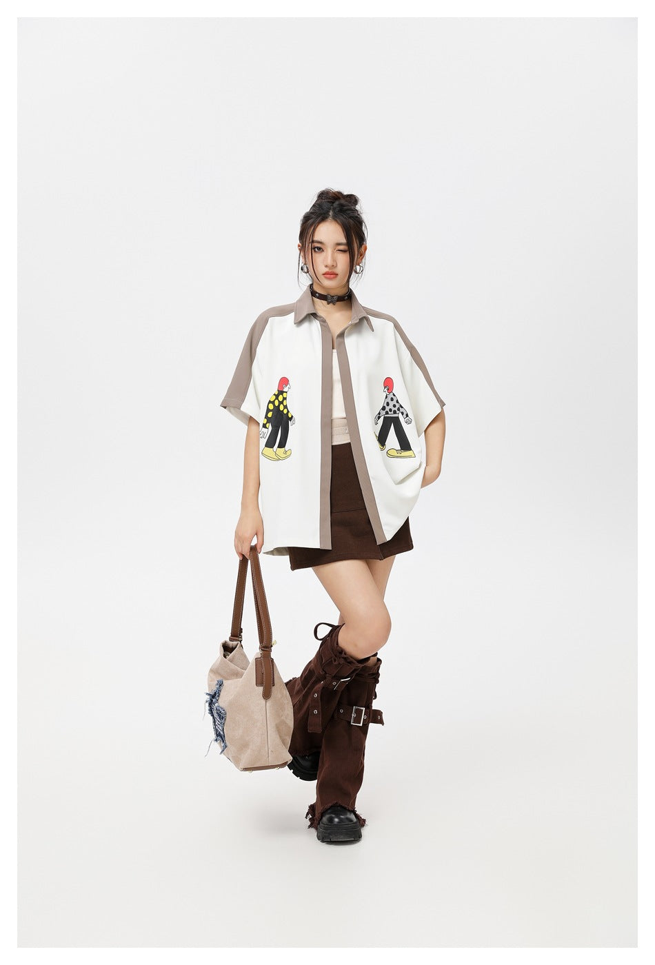 Model posing in an open white shirt with taupe trim and cartoon prints, paired with a dark skirt.