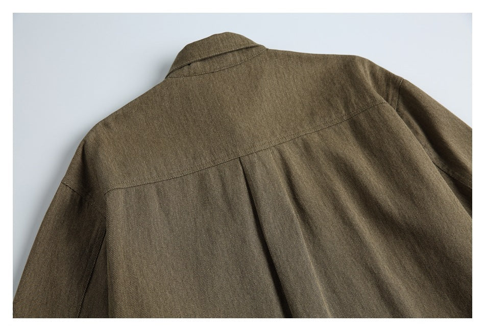 Close-up of the upper back of an olive-brown jacket, showing its collar, yoke seam, and center pleat.