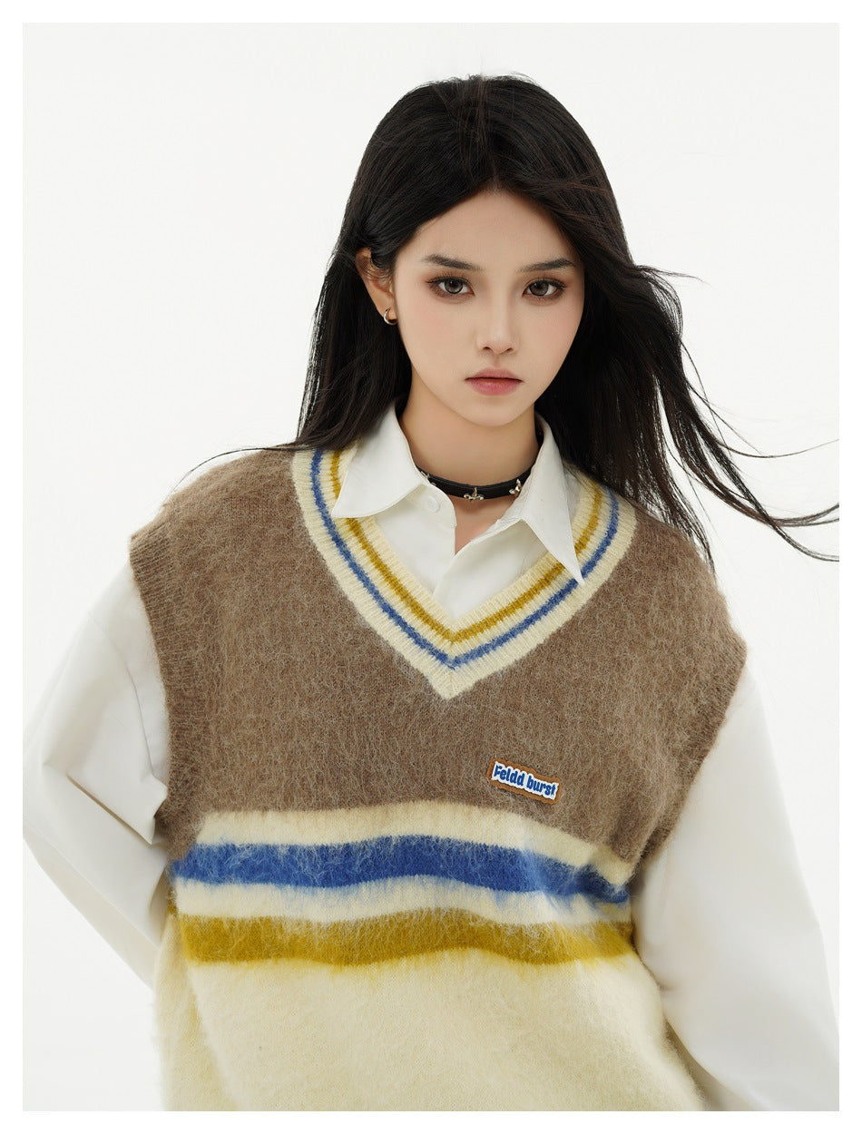 Model wearing a fuzzy brown and cream V-neck sweater vest with blue and mustard stripes over a white shirt.