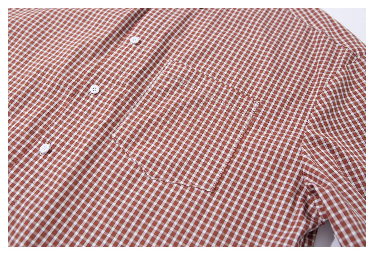 Close-up of the rust-brown and white gingham shirt front, showing its button placket and single chest pocket.
