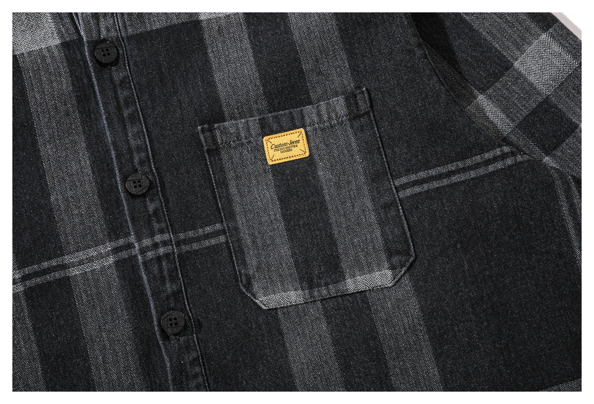 Close-up of a chest pocket and black buttons on the charcoal plaid shirt.