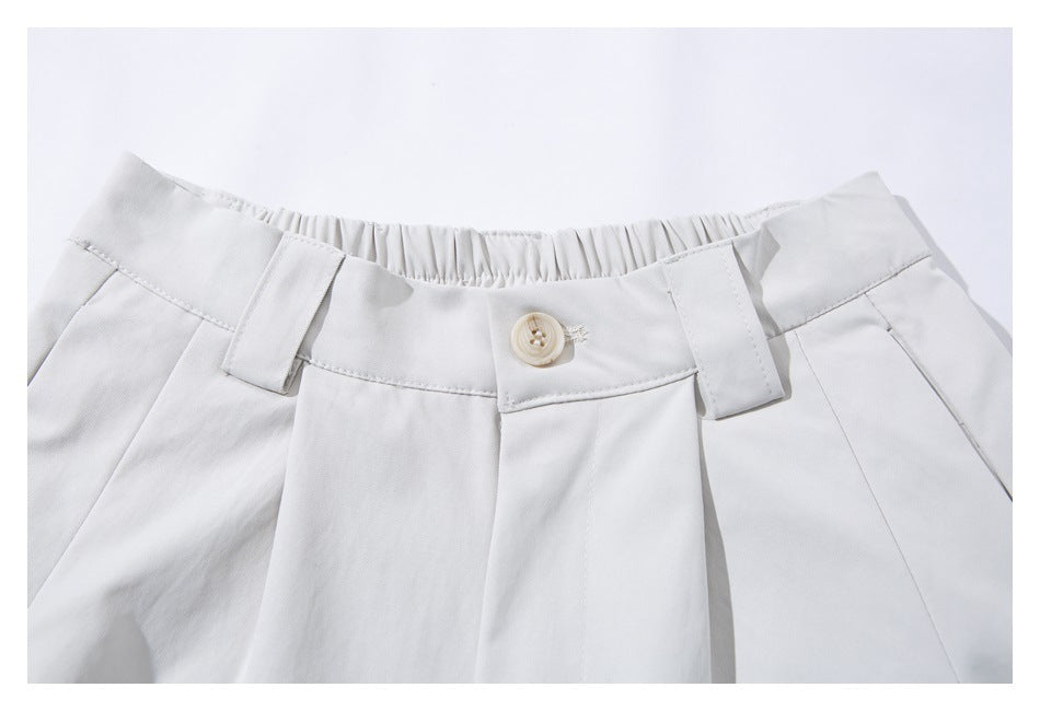 Close-up of the white shorts' waistband, button, belt loops and front pleats.