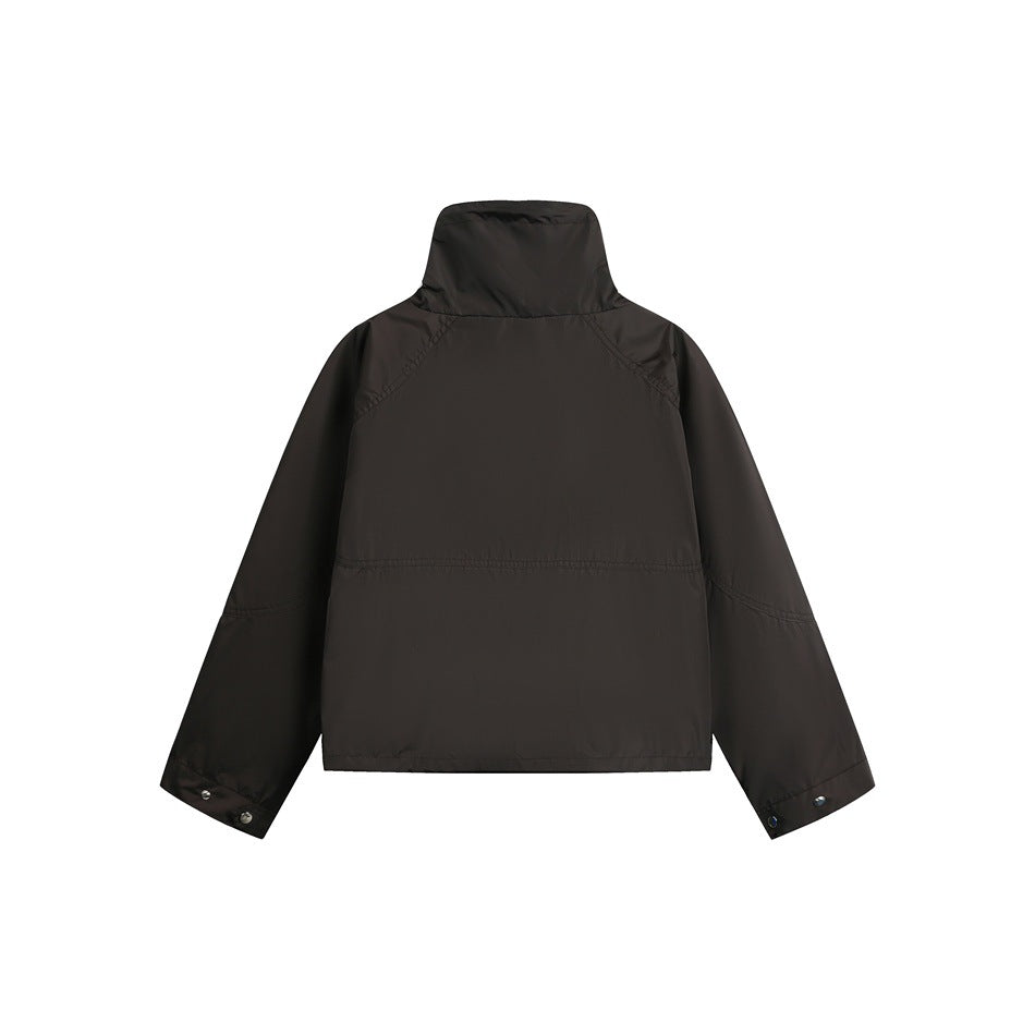 Back of a black jacket with a tall collar, raglan sleeves, and snap cuffs, shown flat against white.