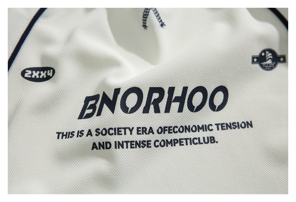 Close-up of dark lettering and small emblems printed on ivory shirt fabric.