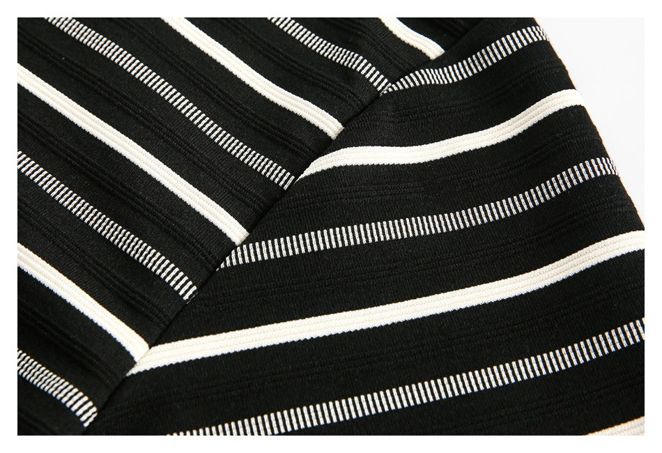 Close-up of a seam in black fabric patterned with cream and narrow white stripes.