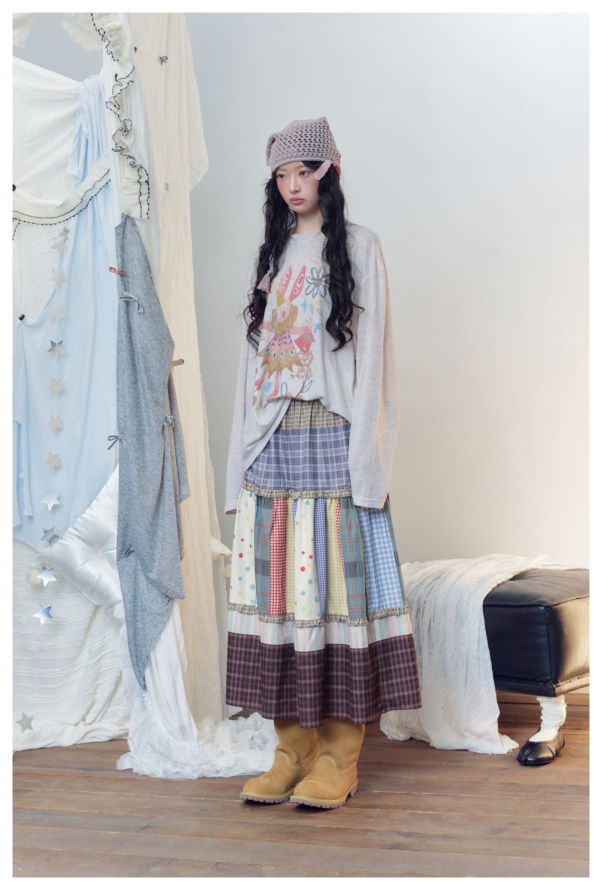 Model wearing a long tiered skirt of mixed plaid, gingham, dots and pastel stripes with a printed top.