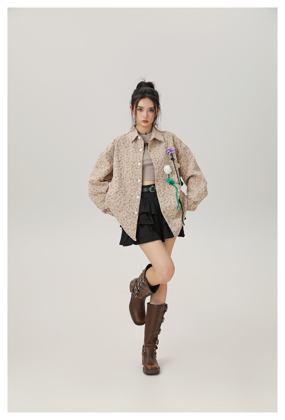 Model wearing the light khaki floral shirt open over a tan crop top, black ruffle skirt and brown boots