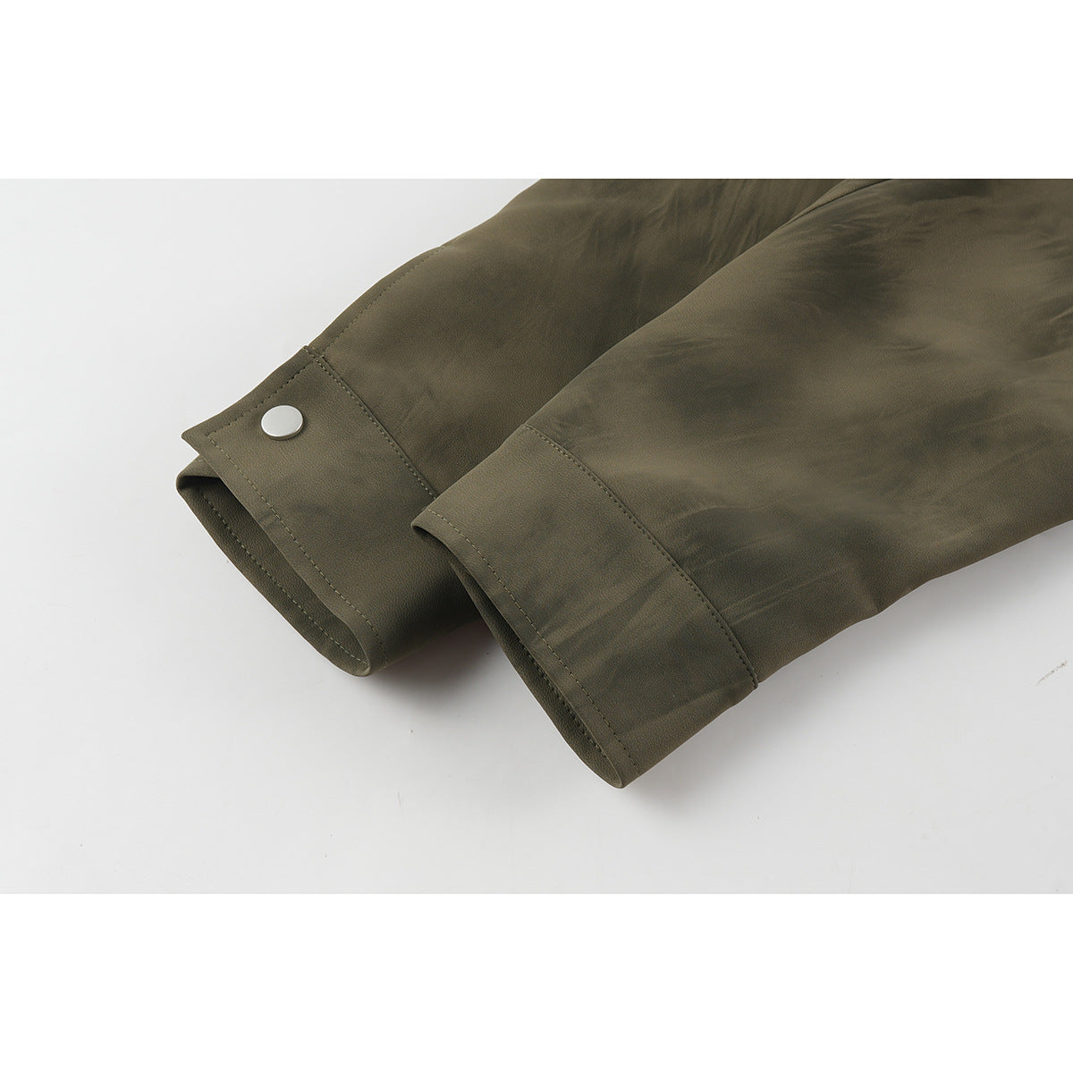 Close-up of two olive-brown jacket sleeve cuffs, one with a snap tab.