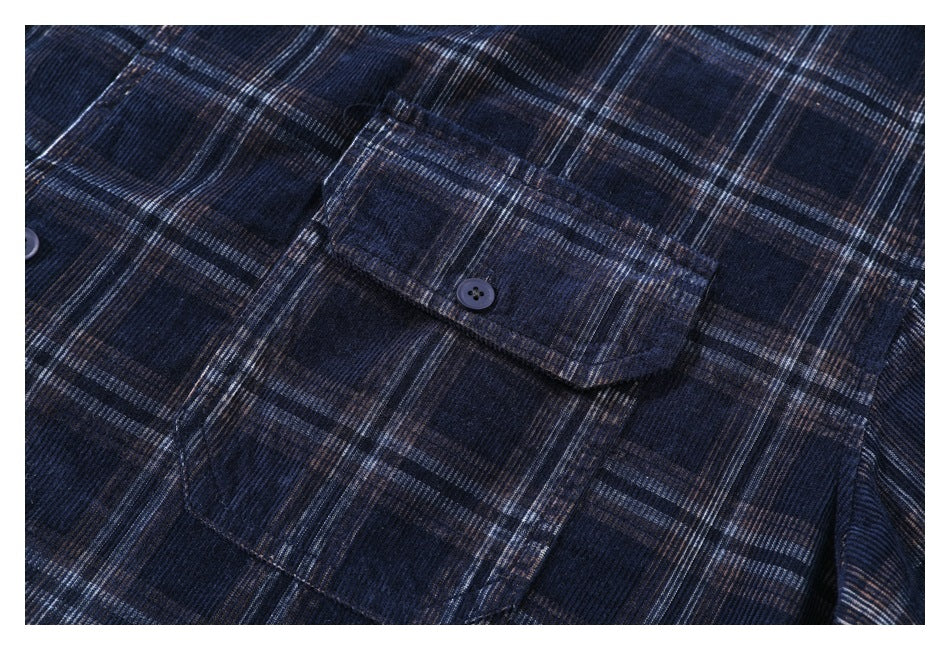 Close-up of a buttoned chest pocket on a dark navy plaid shirt.