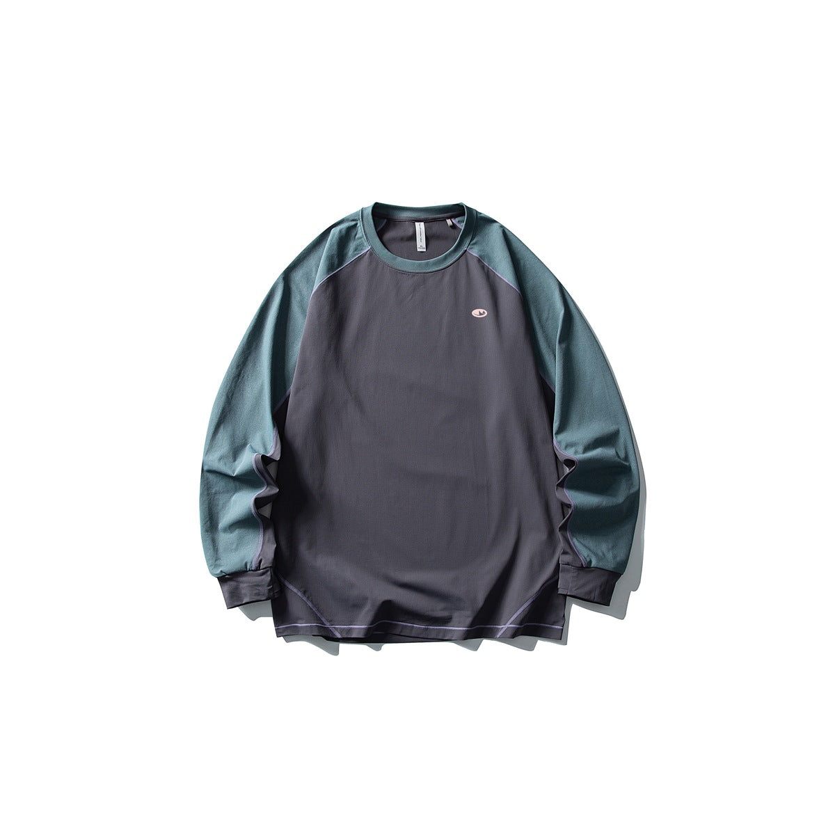 Front of a dark gray long-sleeve raglan tee with teal sleeves, lilac contrast stitching and a small chest logo