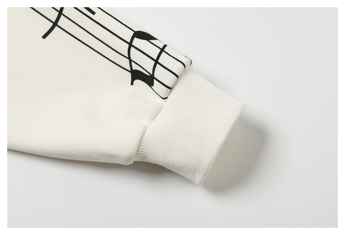 Ivory sleeve cuff with ribbed trim and part of a black musical-staff print.
