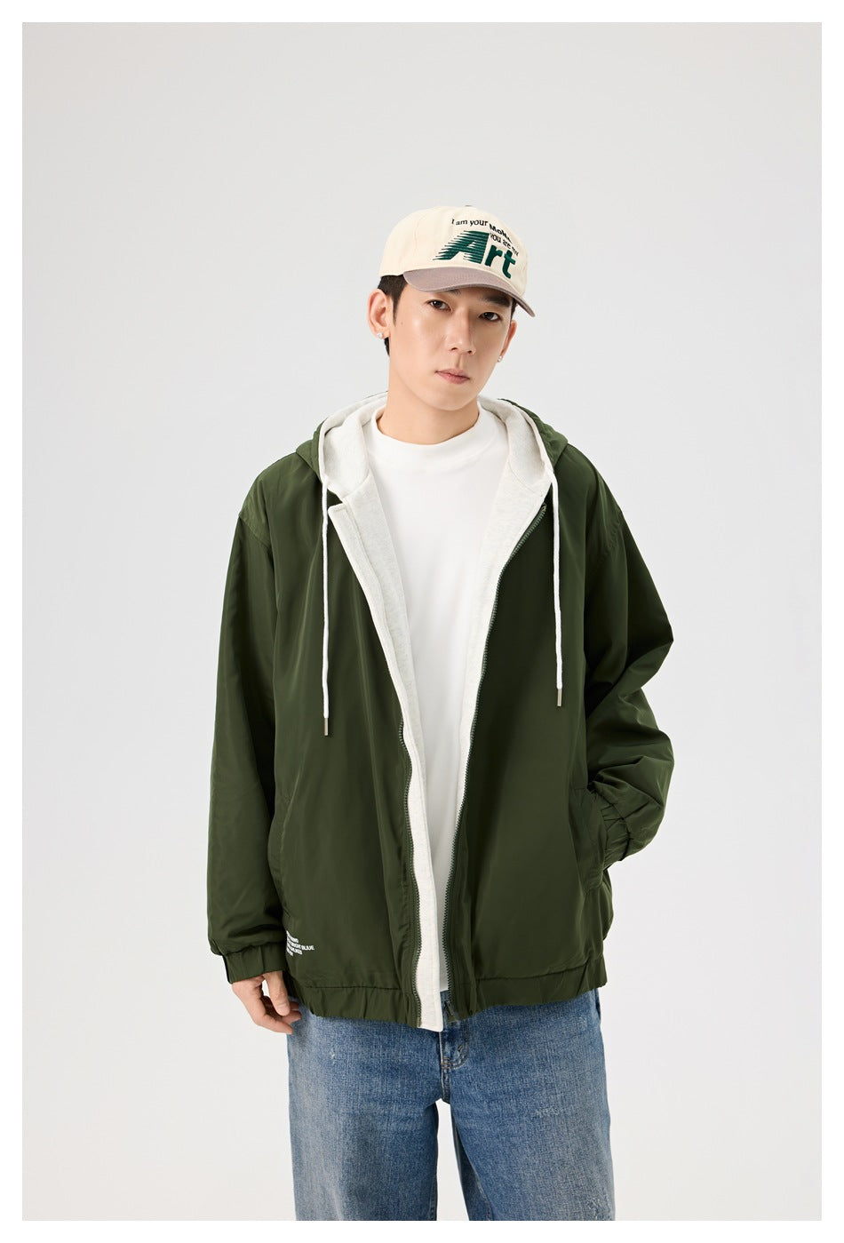 Model wearing an open dark olive hooded jacket, showing its light gray lining and white drawstrings.