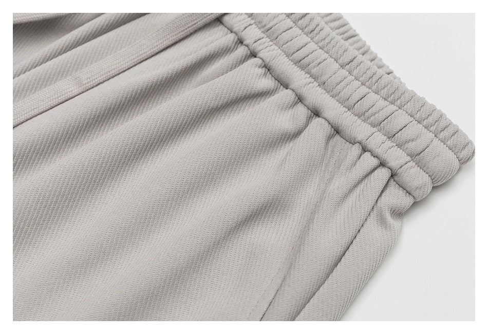 Close-up of a light gray garment's elastic waistband and gathered fabric, with a fabric tie at the edge.