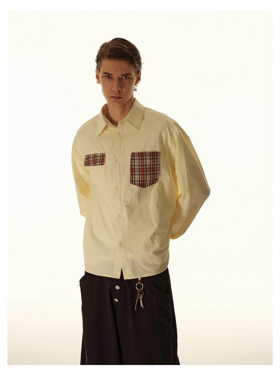 Model in a pale cream button-up shirt with mismatched-size plaid chest pockets, shown from the front.