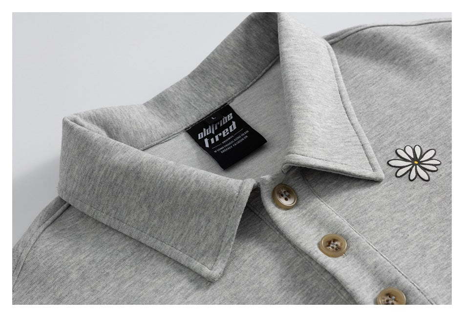 Close-up of a heather-gray collared shirt with tan buttons and a small daisy motif.