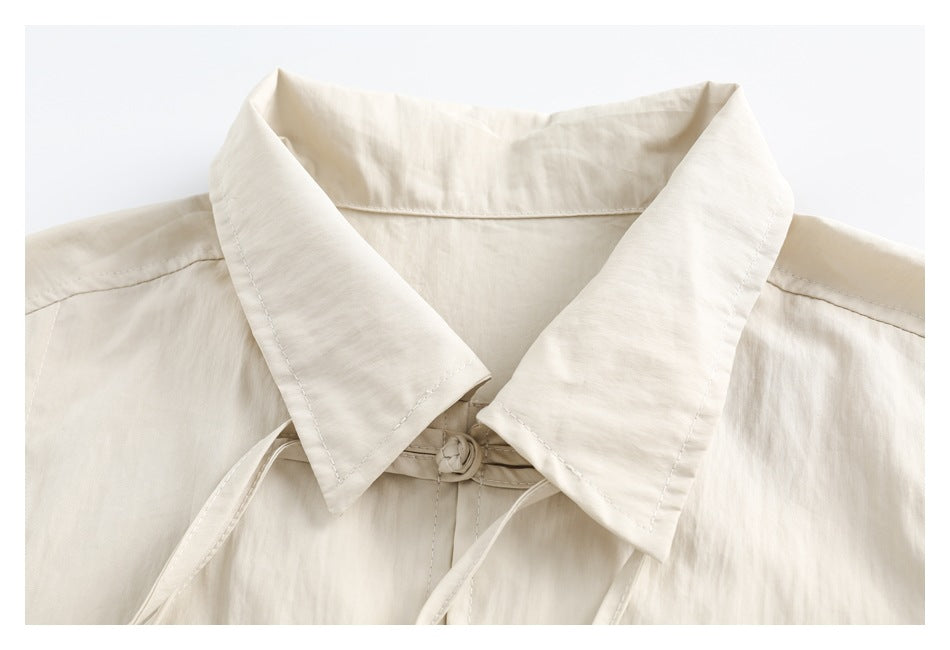 Close-up of a cream shirt's wide collar and knotted frog closure.