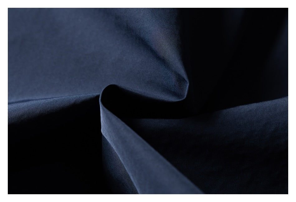 Macro view of smooth navy garment fabric arranged in soft folds.