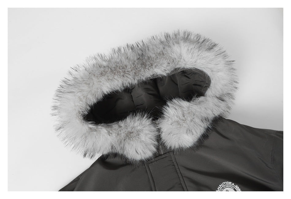Close-up of a charcoal jacket's light gray faux-fur hood trim and partially visible embroidered chest emblem.