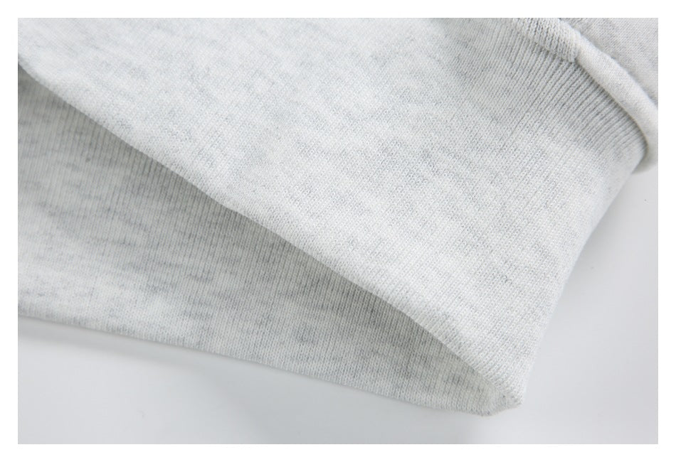Close-up of a light gray heather garment edge with a wide ribbed band and folded seam.